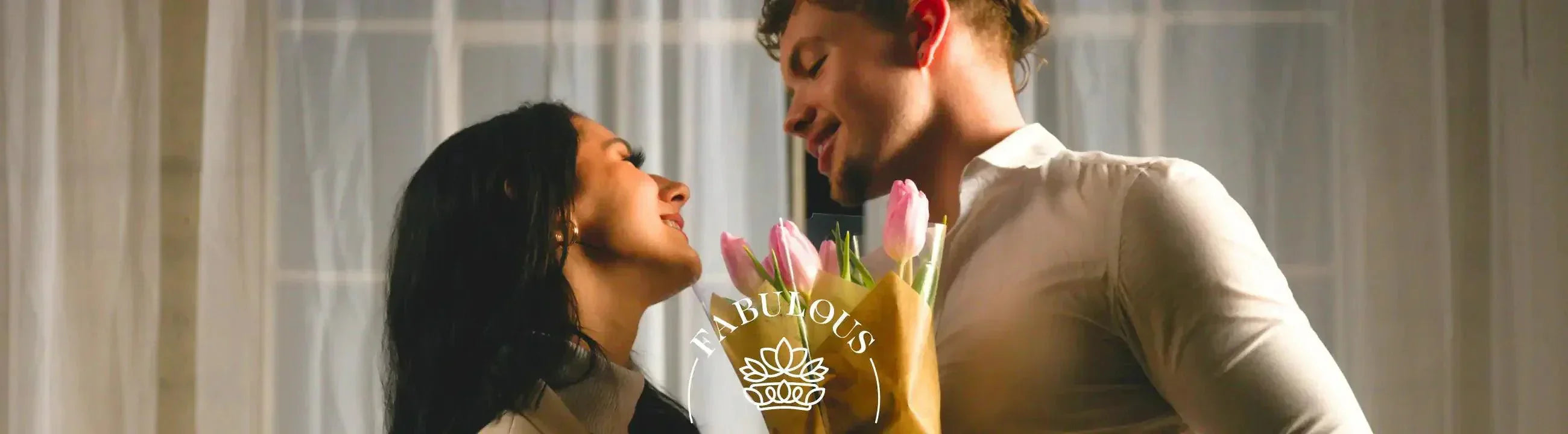 A man presenting a bouquet of tulips to a smiling woman in a warm, intimate setting. Fabulous Flowers and Gifts.
