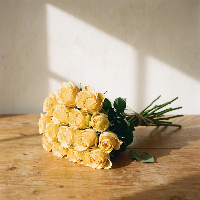 Small Good Morning Rose Bouquet of 12 yellow roses hand-tied with twine, lying on a sunlit pine table, Fabulous Flowers South Africa