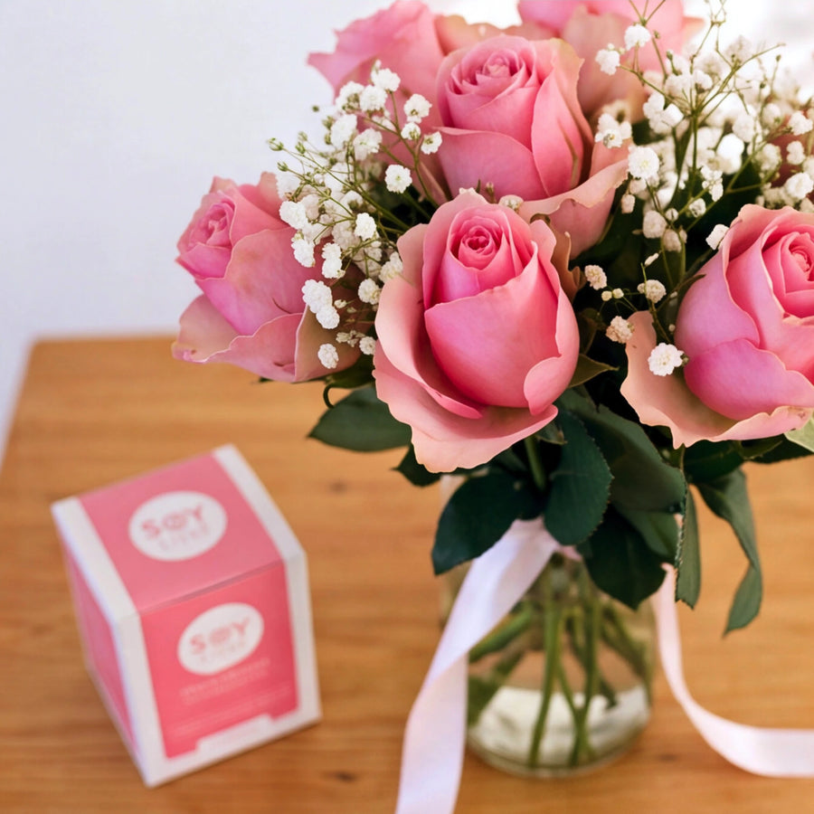 Pink roses with baby’s breath beside a Soy Lites candle in the A Rosy Glow gift set