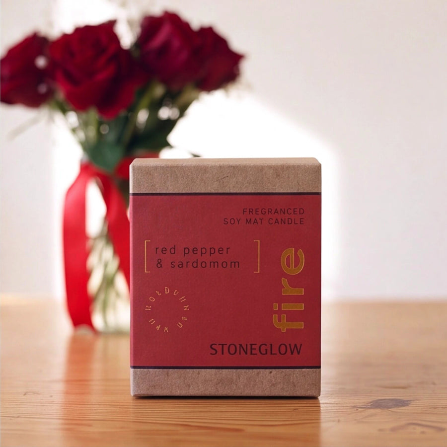 Stoneglow Fire Red Pepper and Cardamom soy wax candle with red roses behind