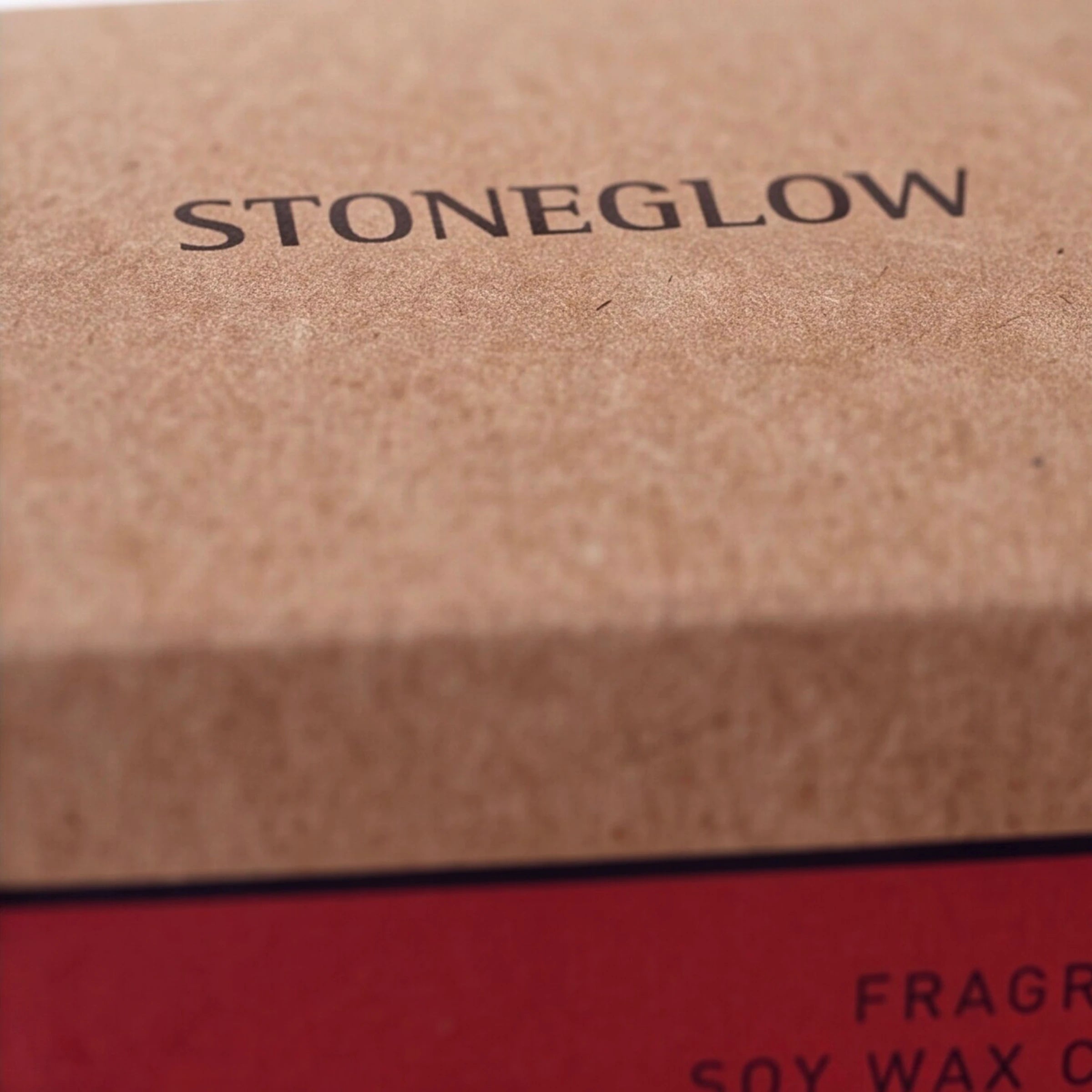 Stoneglow Fire Red Pepper and Cardamom soy wax candle with red roses behind
