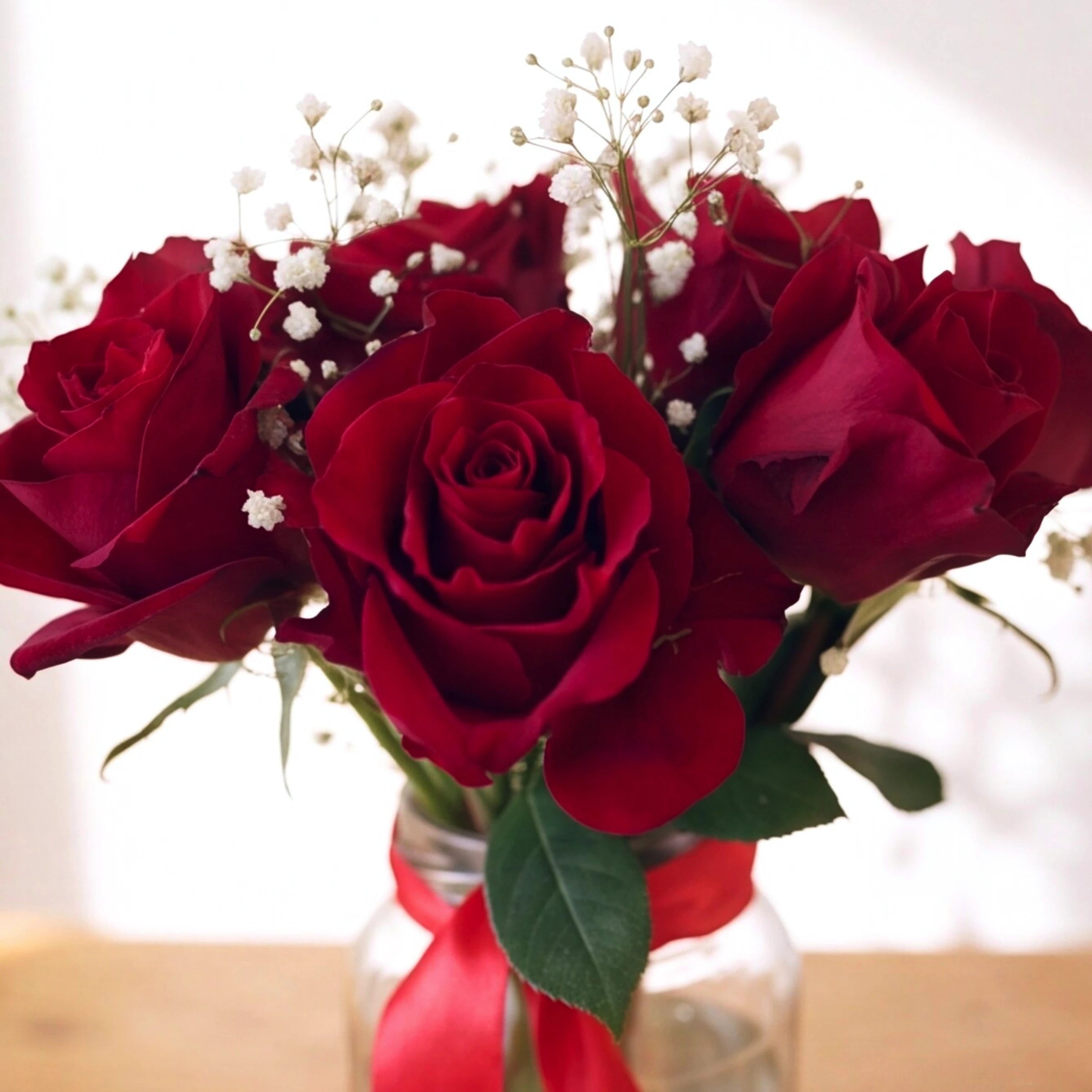 Close-up of deep red roses and white baby's breath in the Ablaze with Love arrangement