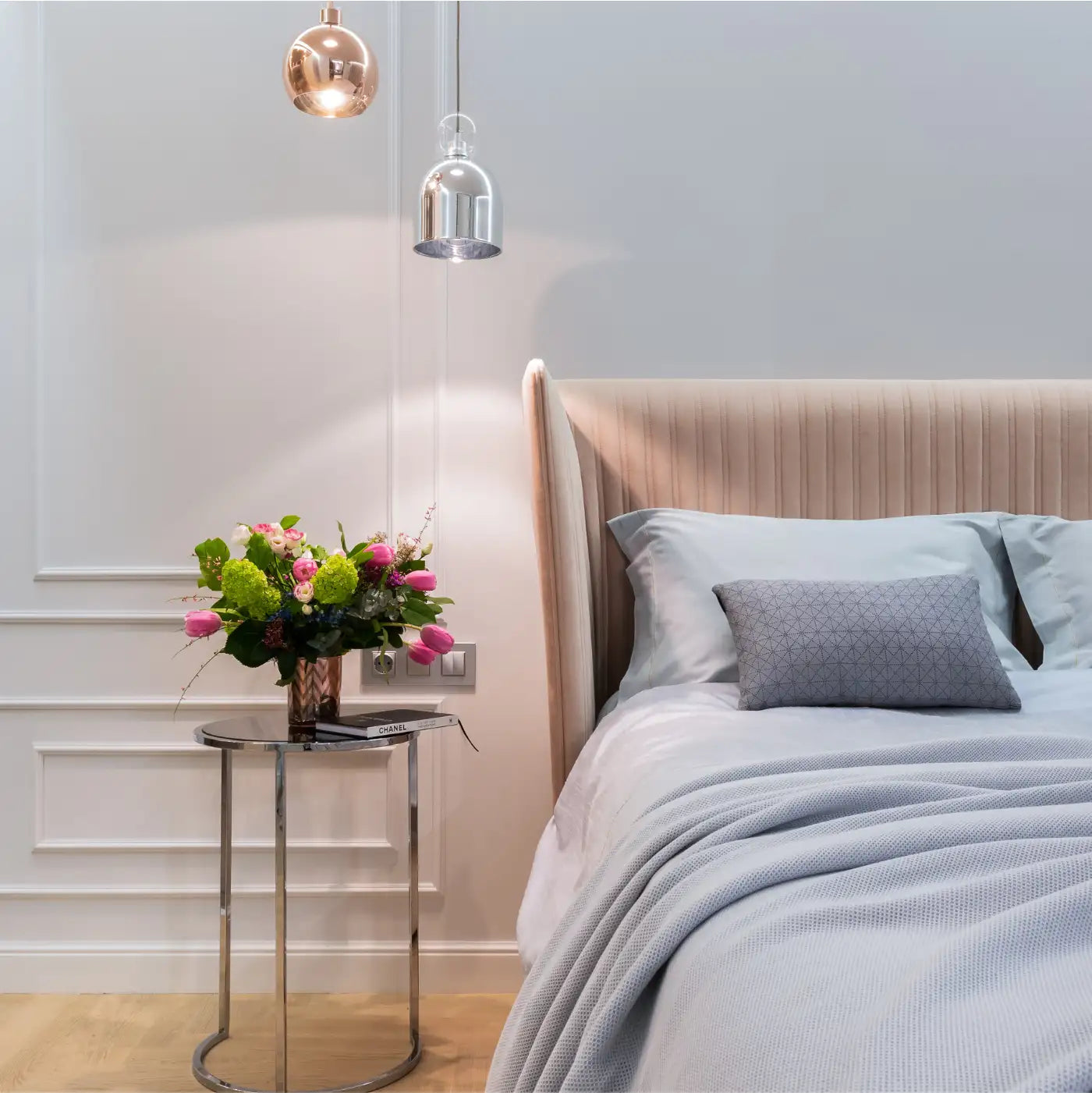 Elegant bedroom with a plush bed, grey linens, and a bedside table with a floral arrangement. Fabulous Flowers and Gifts. Airbnb, Guest House and Hotel.