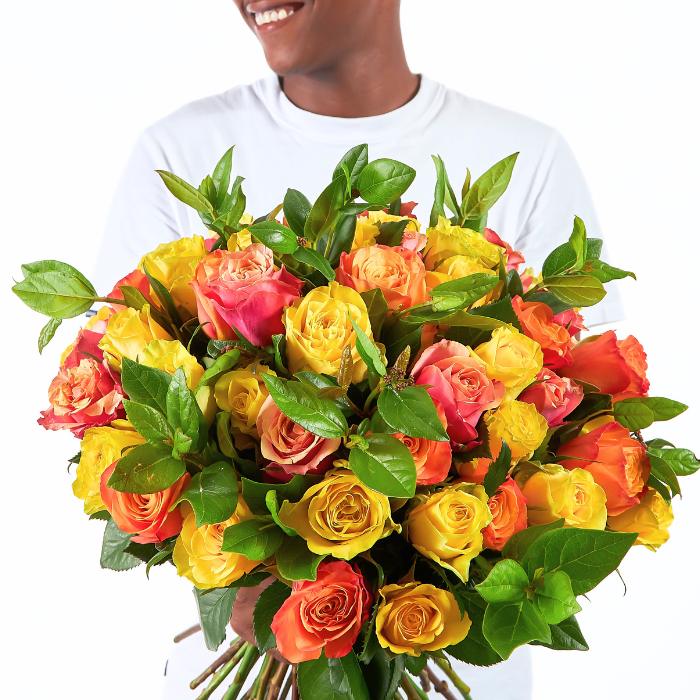 Person holding a bouquet of colorful roses with a white background