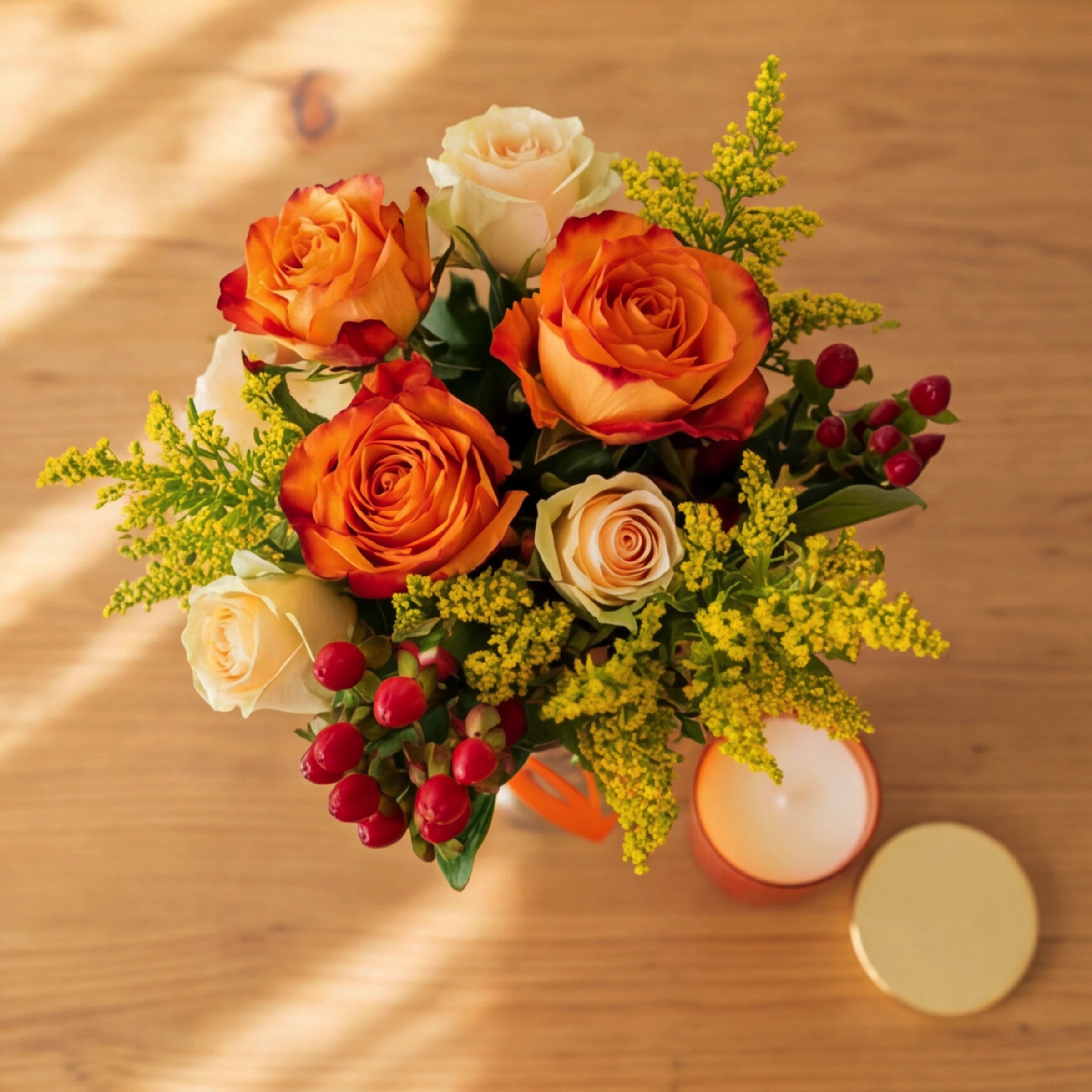 Top-down view of the Amber & Spice posy, orange and cream roses, red berries and yellow solidago