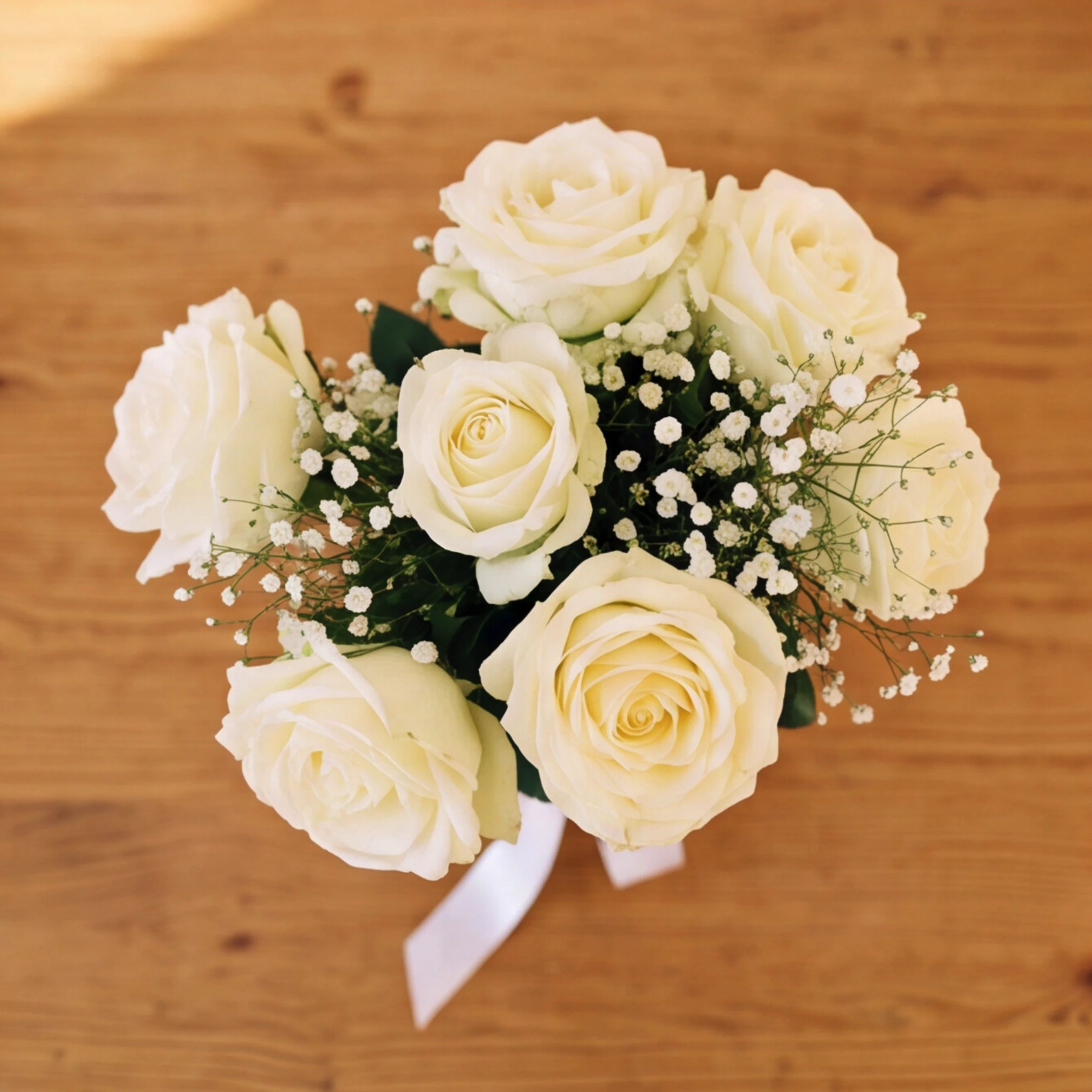 White roses and baby's breath viewed from above, Angel White jar arrangement on a wooden table