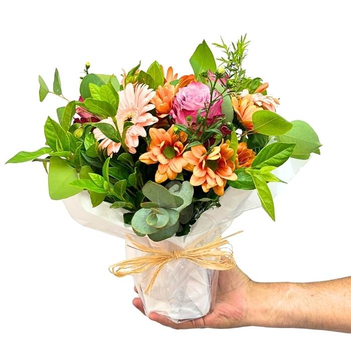 Posy of flowers held by a hand on a white background