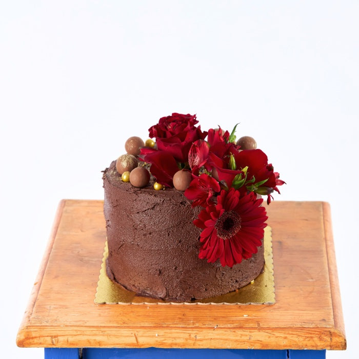 Blooming Red Velvet Delight - Fabulous Flowers & Gifts chocolate cake topped with red roses, gerberas and chocolate balls.