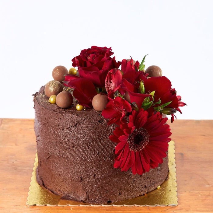 Blooming Red Velvet Delight - Fabulous Flowers & Gifts close-up of red velvet cake with fresh red flowers and chocolate pearls.