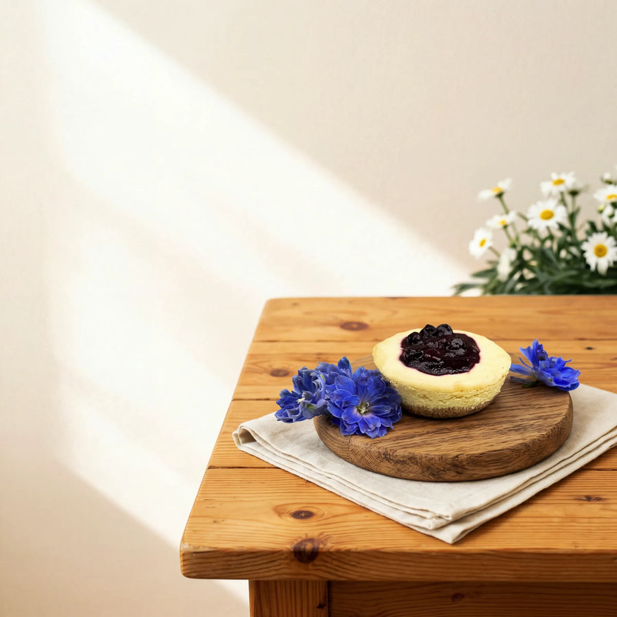 Blueberry Cheesecake on a serving board with blue delphinium and white daisies by Fabulous Flowers