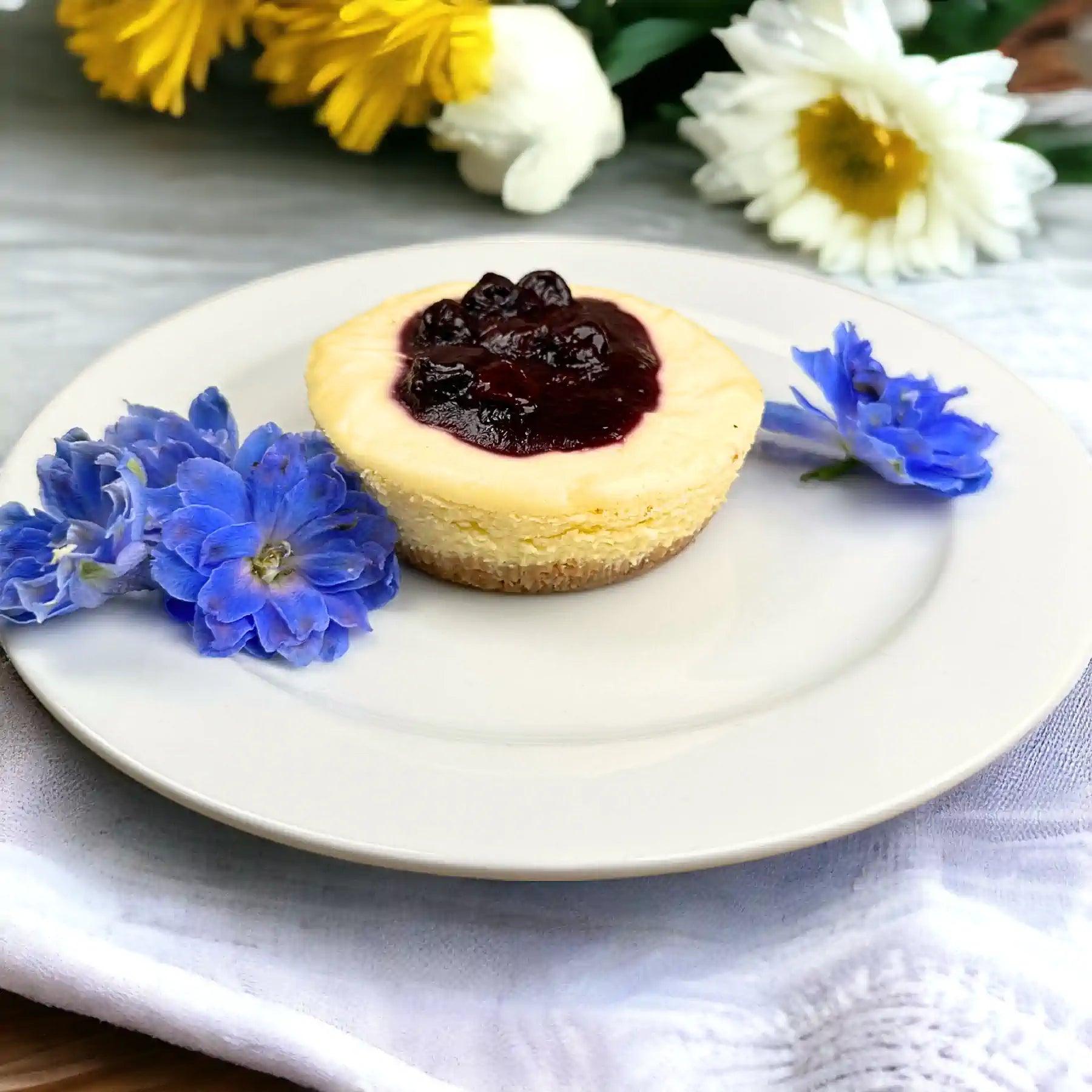 Sumptuous blueberry cheesecake with a golden crust, garnished with fresh blueberry sauce and blue flowers. Fabulous Flowers and Gifts.