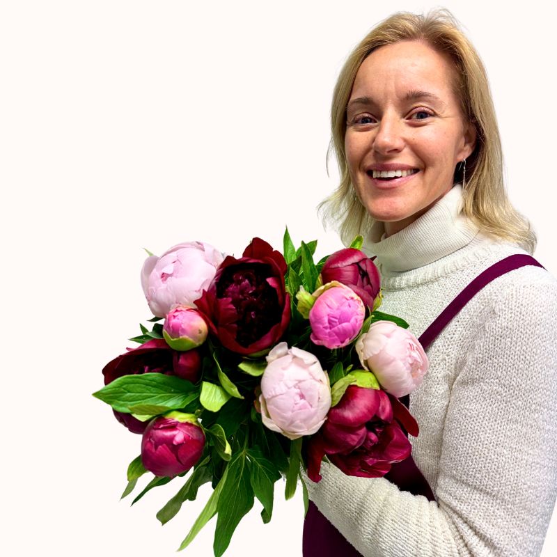 Blush & Merlot - Fabulous Flowers and Gifts bouquet held by a smiling florist wearing a white jumper and maroon apron