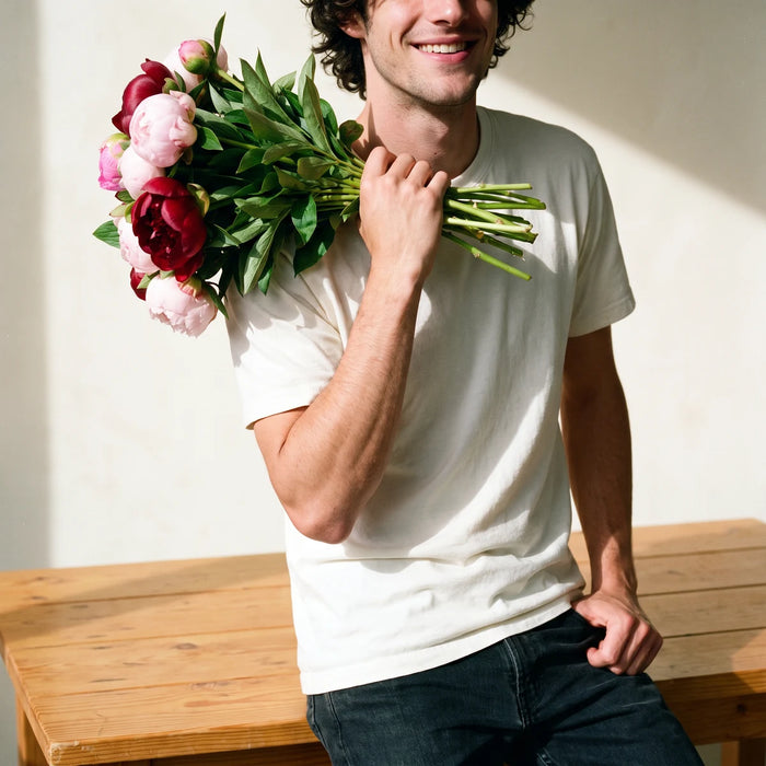 Man holding a blush and merlot peony bouquet over his shoulder