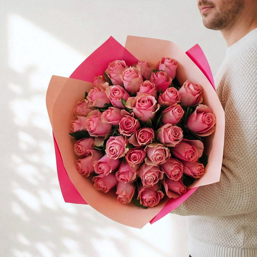 The largest Bonbon, three dozen pink roses in a two-tone pink wrap, held by a Fabulous Flowers florist