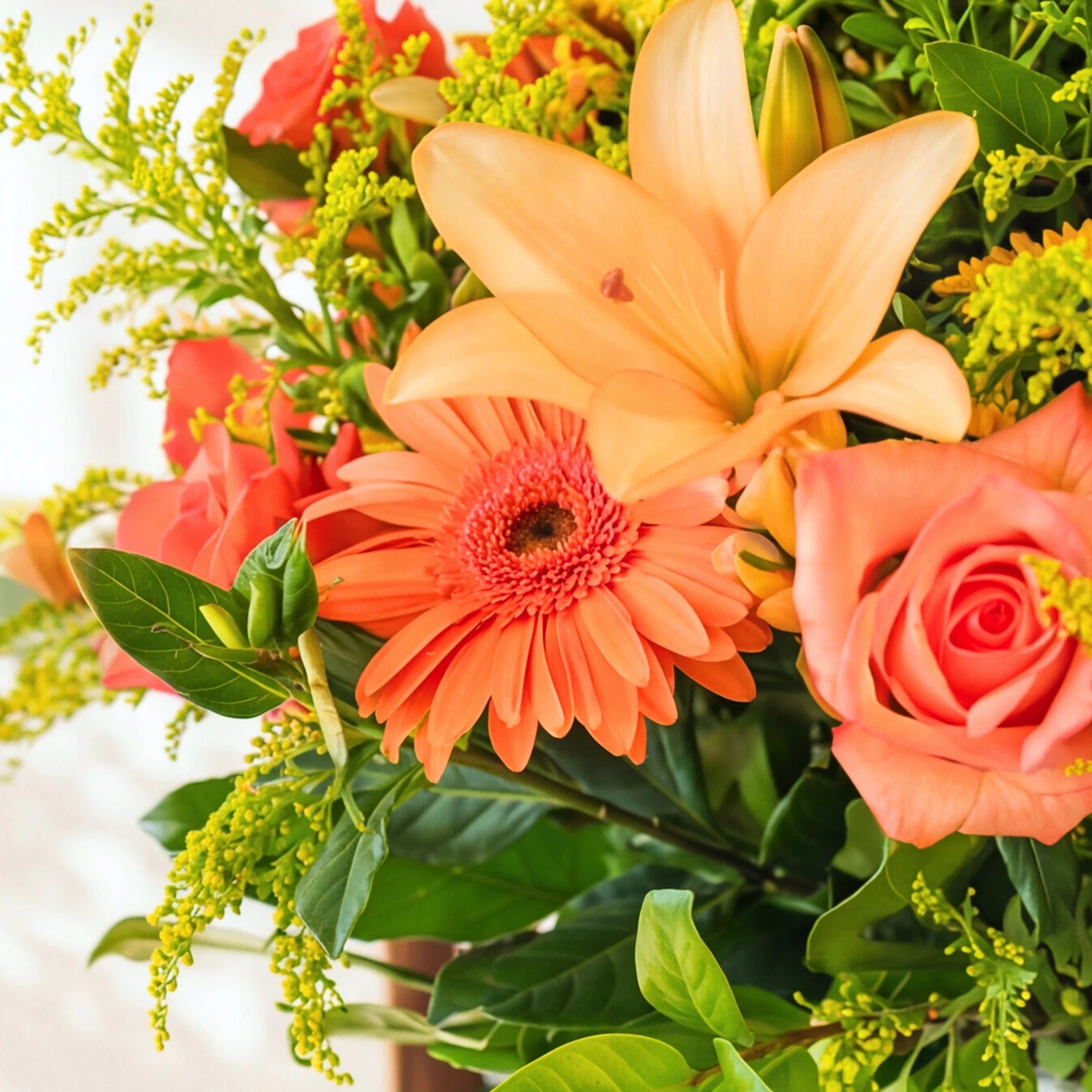 Close-up of a peach lily, orange gerbera and coral rose in the Bright Orange Glass Vase