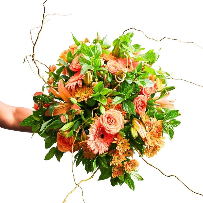 Bouquet of flowers with greenery held by a person on a white background