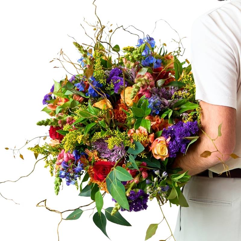 Colorful bouquet of flowers held by a person on a white background