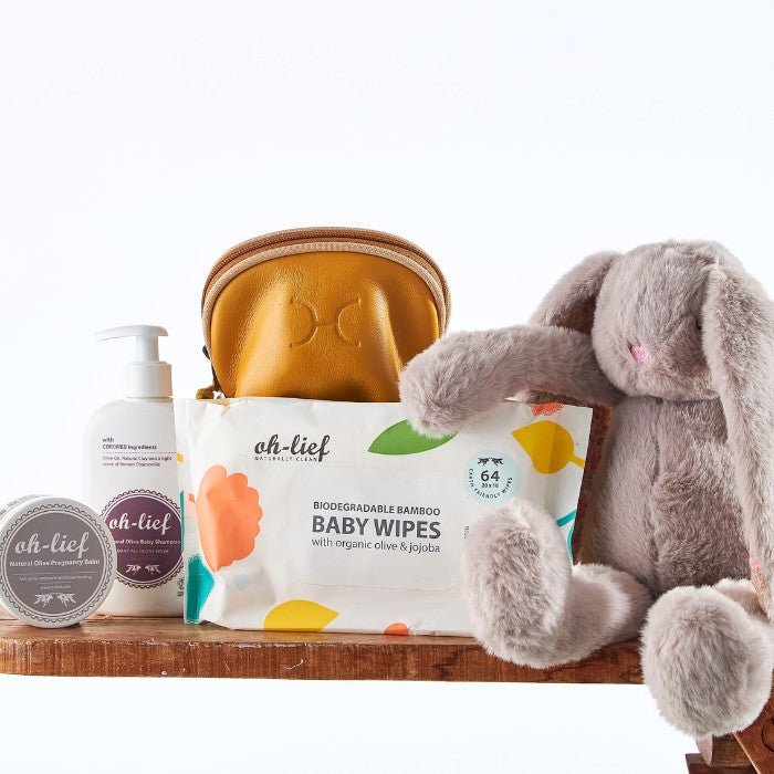 Complete Bunny Love Baby Kit with a soft grey bunny, organic skincare items, and eco-friendly wipes, arranged next to a mustard yellow pouch.