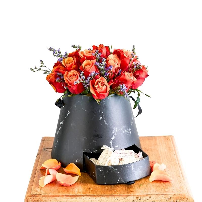 Floral arrangement in a black marble vase on a wooden board with peaches.