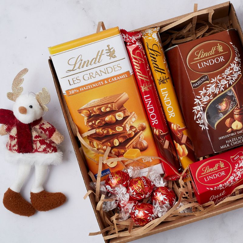 Gift box with assorted Lindt chocolates and a festive reindeer ornament.
