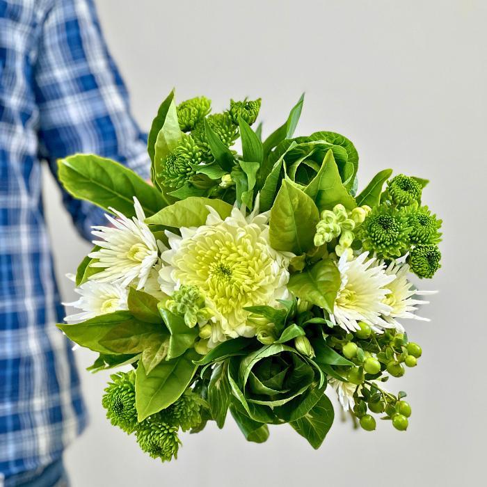 Chrysanthemum Charm bouquet – crisp white blooms, green accents, and bold foliage, hand-held by florist in plaid shirt