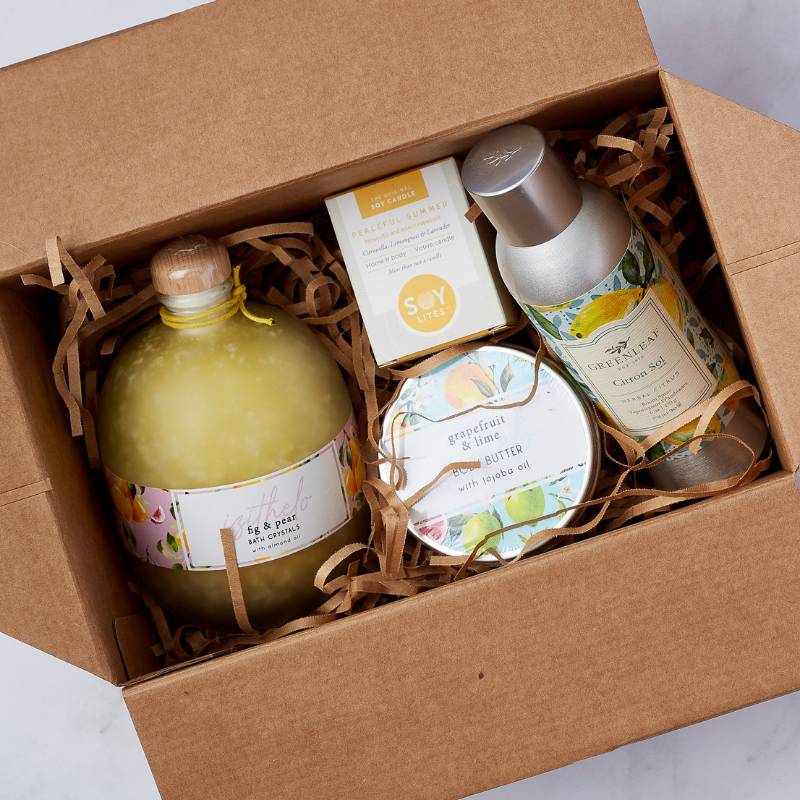 Close-up view of Citrus Bliss Gift Box - showcasing fig & pear bath crystals, grapefruit & lime body butter, citronella room spray, and a peaceful summer soy candle.