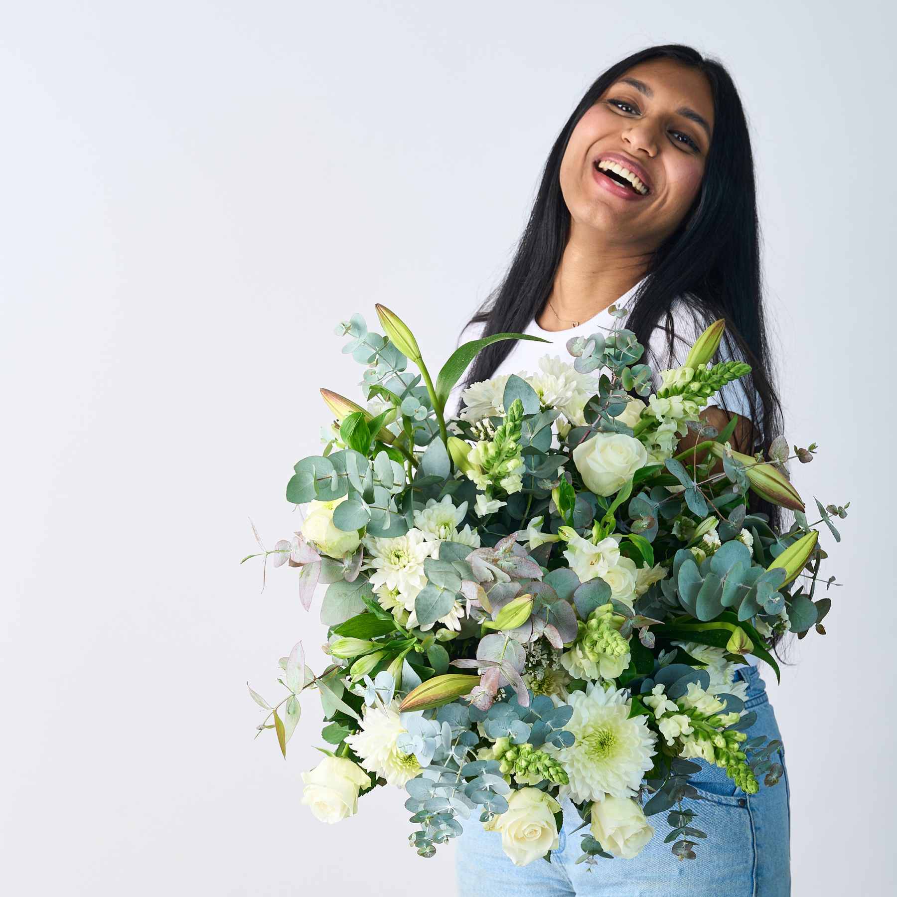 Laughing woman holding a Classic White Bouquet, showcasing a blend of white blooms and fresh greenery.