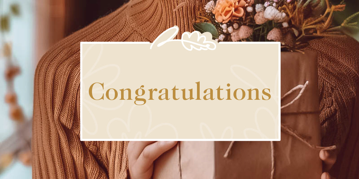 A person presenting a beautifully wrapped gift box with floral decorations for congratulations. Fabulous Flowers and Gifts - Congratulations