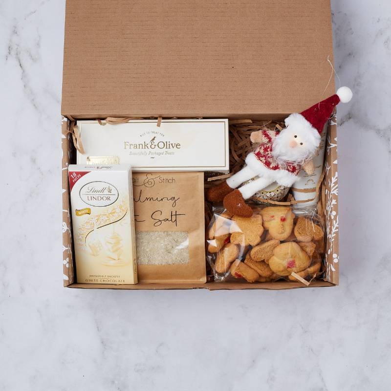 Cosy Christmas Treats Gift Box featuring white Lindt chocolate, Frank & Olive treats, calming salt, and a cute Santa decoration.