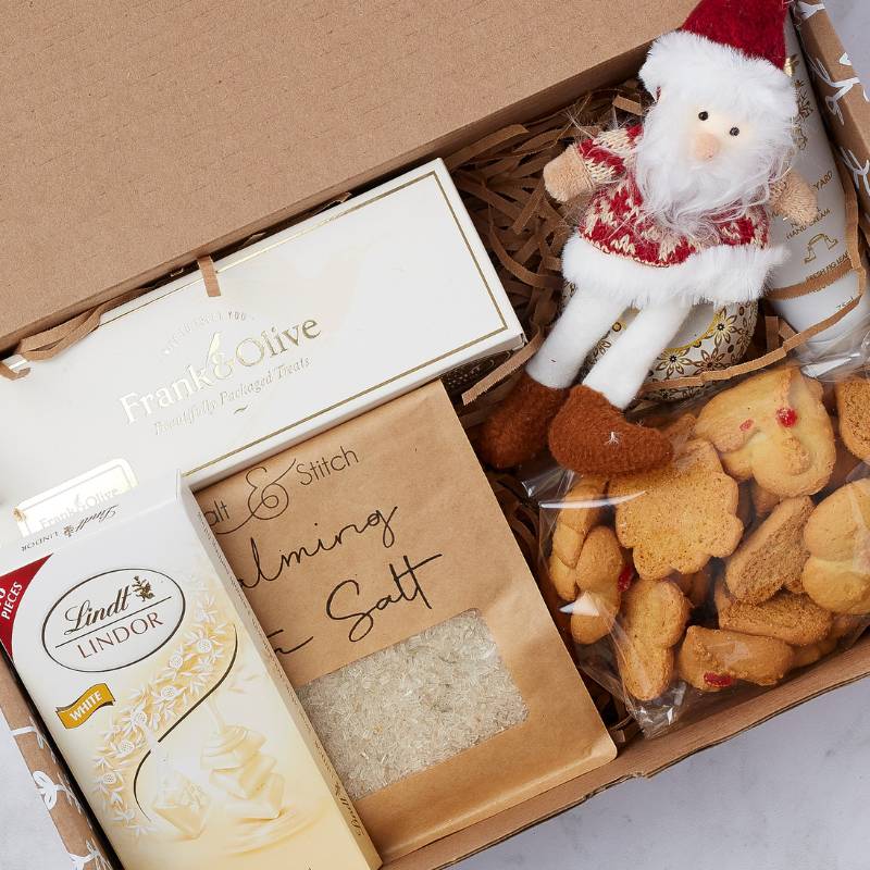 Close-up of Cosy Christmas Treats Gift Box with Lindt chocolate, Frank & Olive treats, calming salt, and Santa decoration.