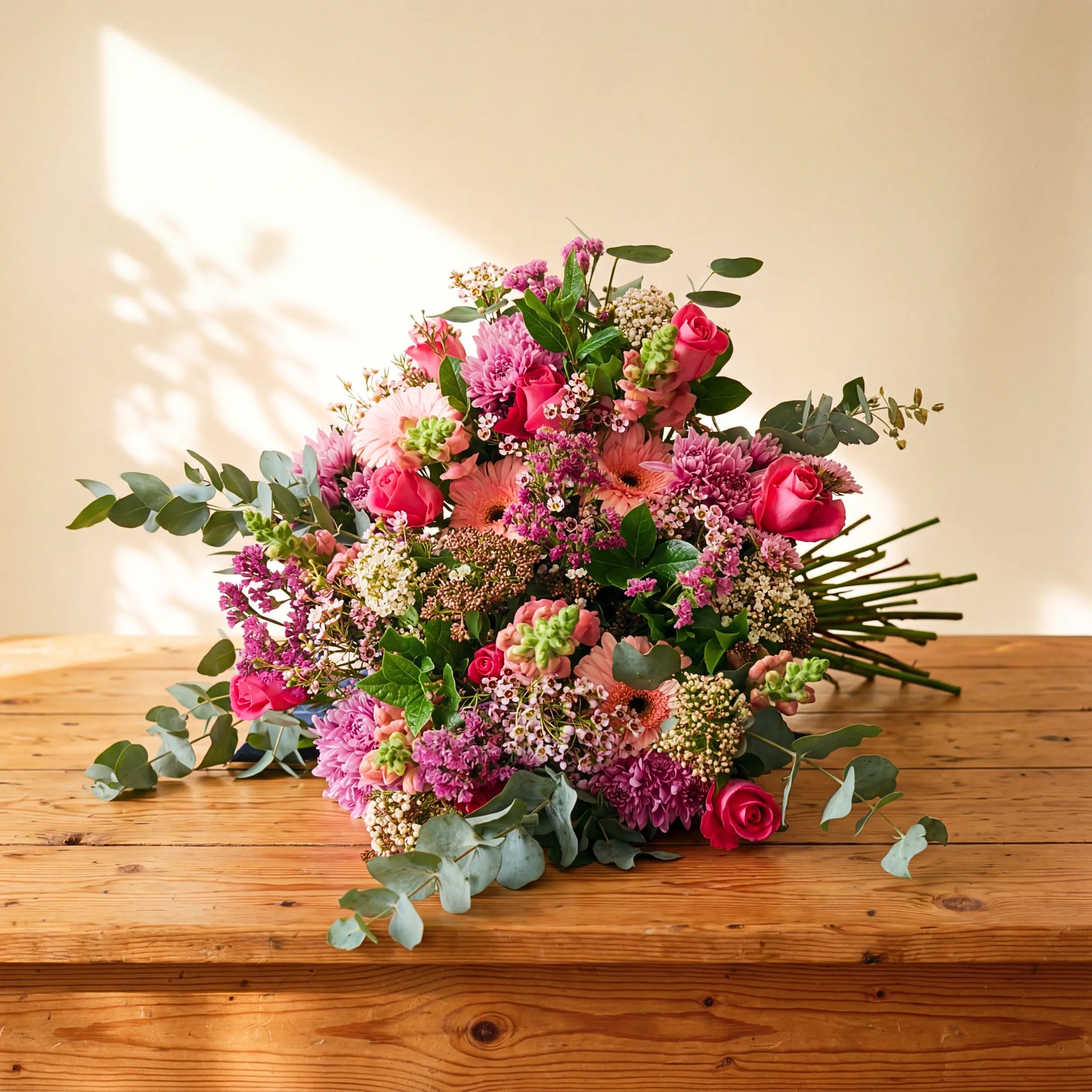 Country Garden Bouquet wild meadow hand-tied bouquet of pink roses, gerbera, chrysanthemums and eucalyptus on a wooden table