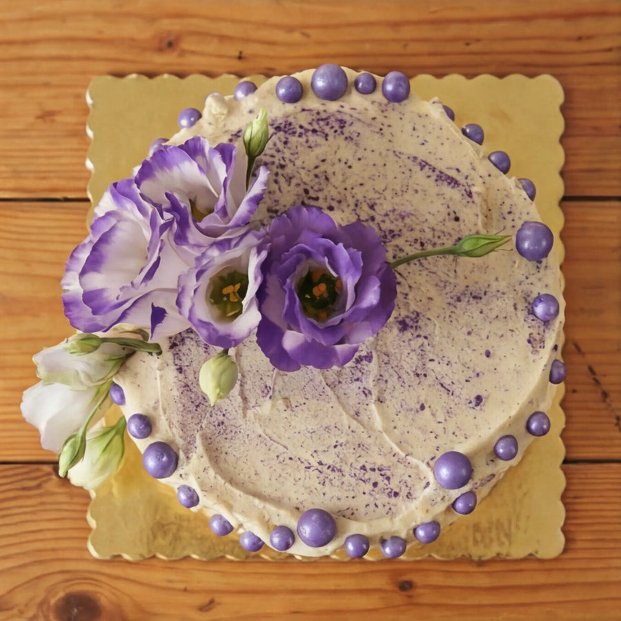 Overhead view of Creamy Violet Dream Cake showing purple speckled buttercream top and lisianthus crown