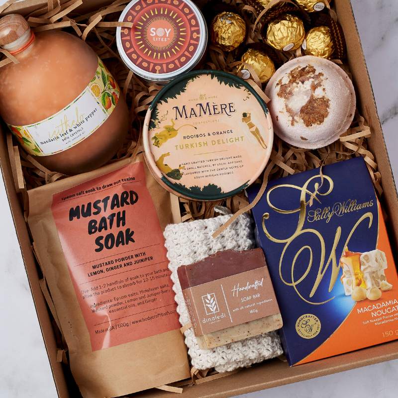 Close-up of the Deluxe Pamper Gift Box with bath soak, Turkish delight, bath bomb, handmade soap, macadamia nougat, and Ferrero Rocher.