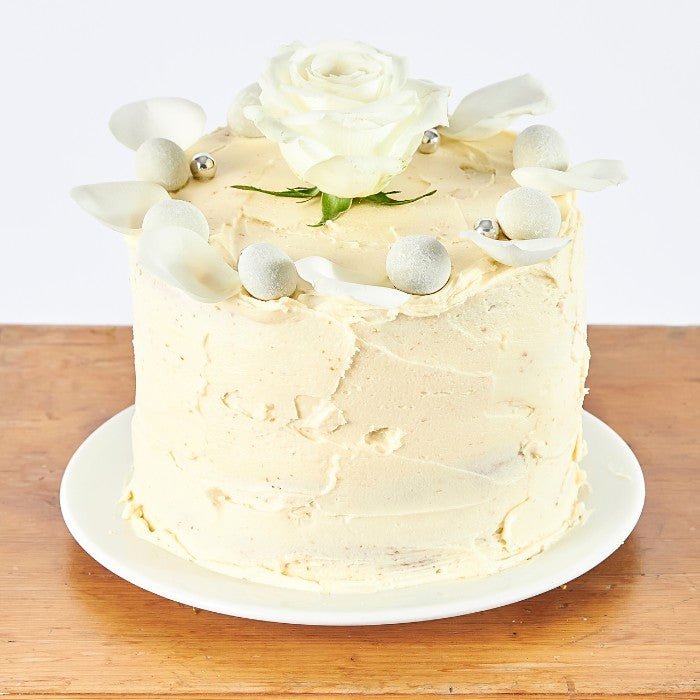 Close-up of an Elegant Rose Celebration Cake with intricate white floral decorations and edible silver accents, perfect for weddings or sophisticated celebrations.