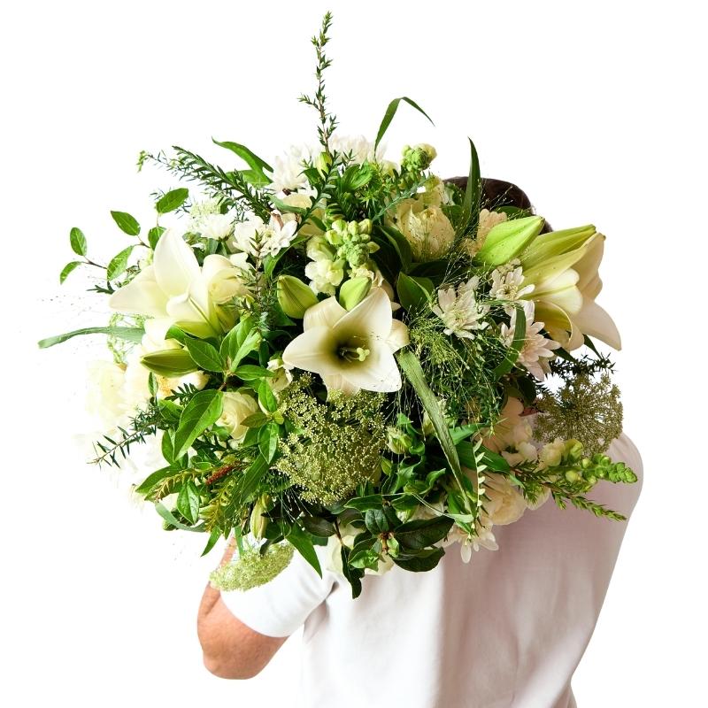 Front view of elegant white bouquet with lilies, roses and textured green foliage
