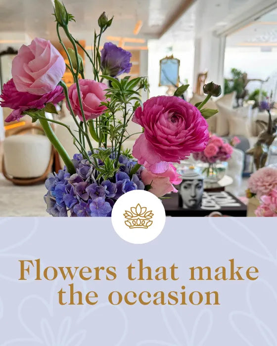 Floral arrangement with pink and purple flowers in a vase, set against a blurred indoor background.