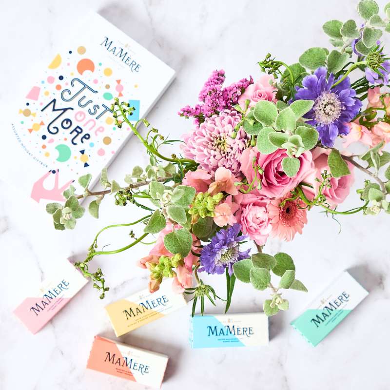 Floral arrangement with 'MaMere' branded cards and boxes on a white background