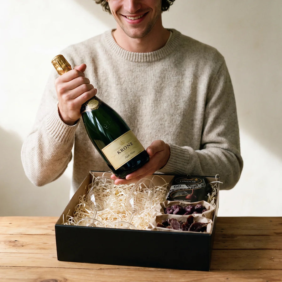 Smiling man lifting a bottle of Krone sparkling wine out of an open gift box, Fabulous Flowers South Africa