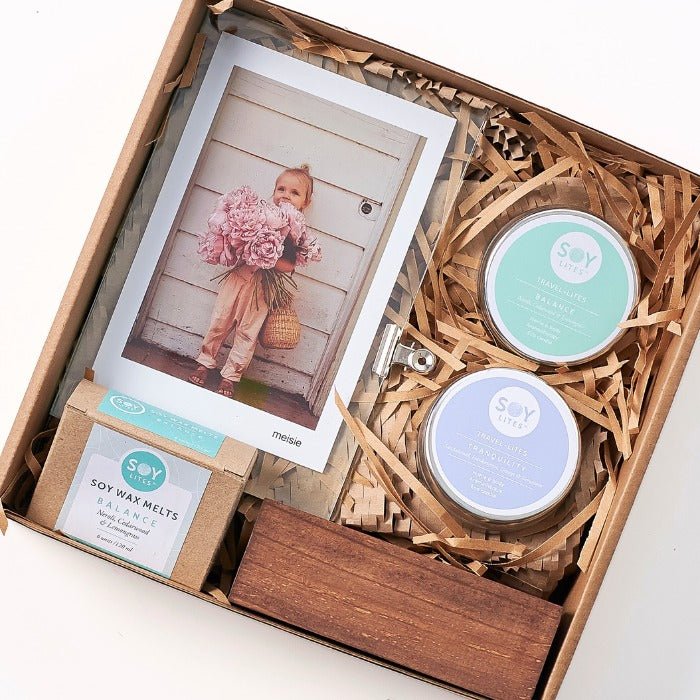 Peaceful wellness gift set featuring soy wax melts, travel candles, and a charming floral photograph in frame.