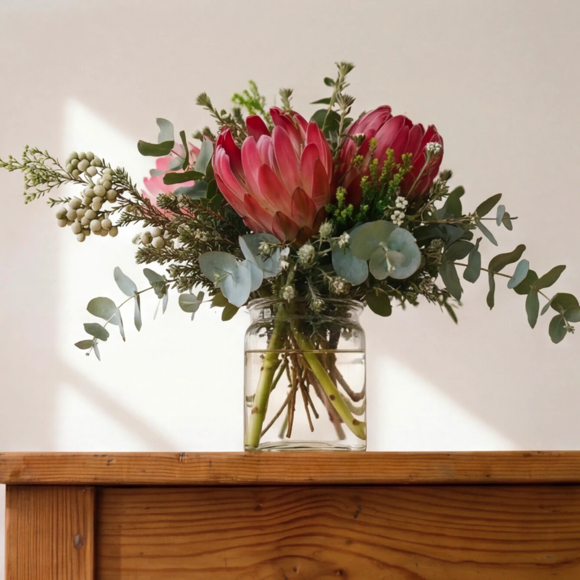 Cape fynbos posy in a glass jar on a wooden table, indigenous flower gift from Fabulous Flowers Claremont studio
