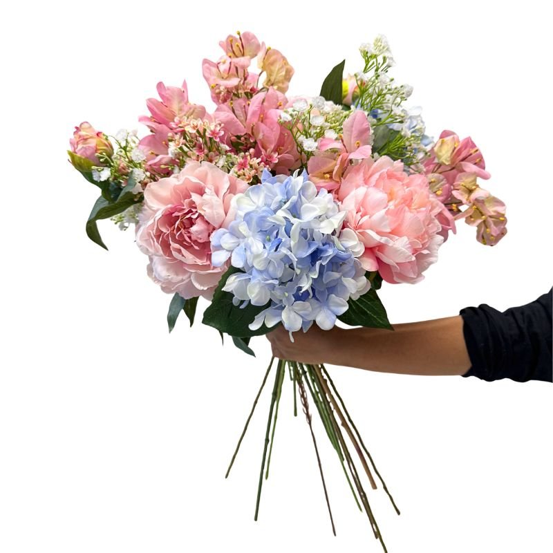 Bouquet of pink and blue flowers held by a person against a white background