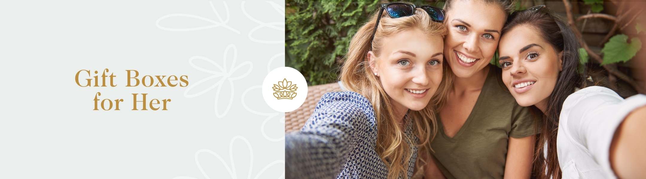 Gift Boxes for Her text beside a group of three smiling women taking a selfie outdoors in a lush, green setting.
