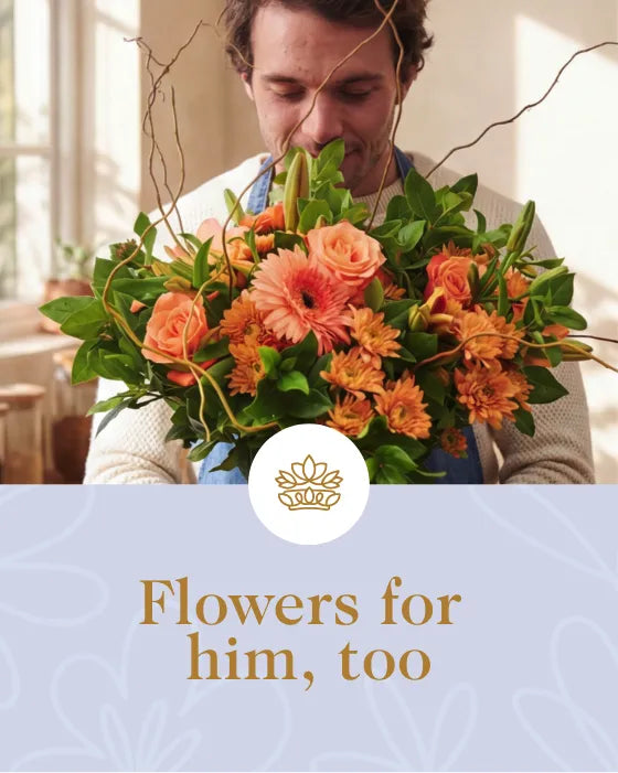 Man holding a lush orange flower bouquet in a sunlit kitchen