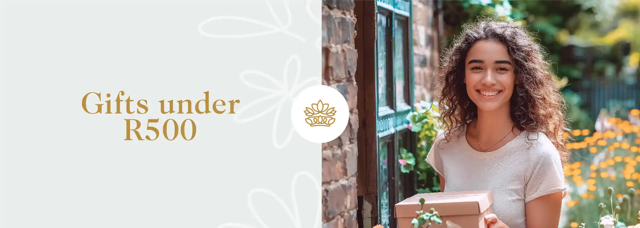 A smiling woman holding a gift box outdoors next to a 'Gifts Under R500' banner, from the Gifts Under R500 Collection at Fabulous Flowers and Gifts.