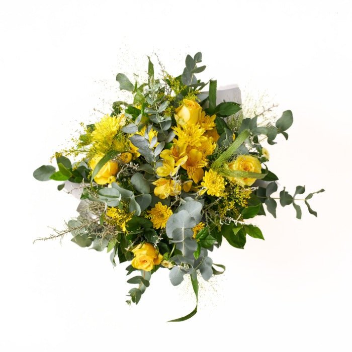 Top view of a lush floral arrangement with yellow roses and complementary wildflowers in a white and gold pot, perfect for festive occasions.