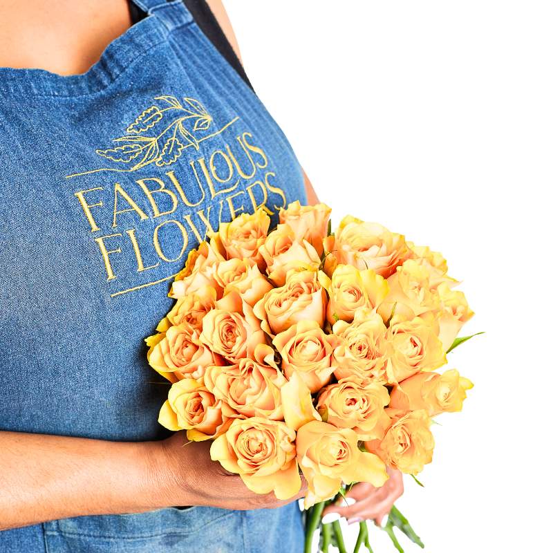 Person holding a bouquet of yellow roses wearing a 'Fabulous Flowers' apron.
