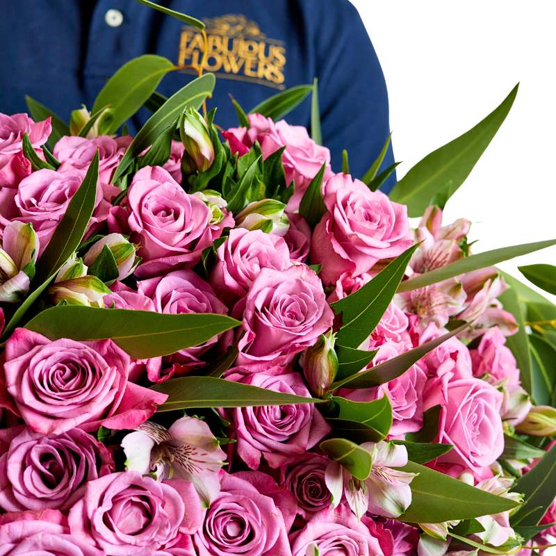 Bouquet of pink roses with a person wearing a blue shirt with 'Fabulous Flowers' branding in the background.