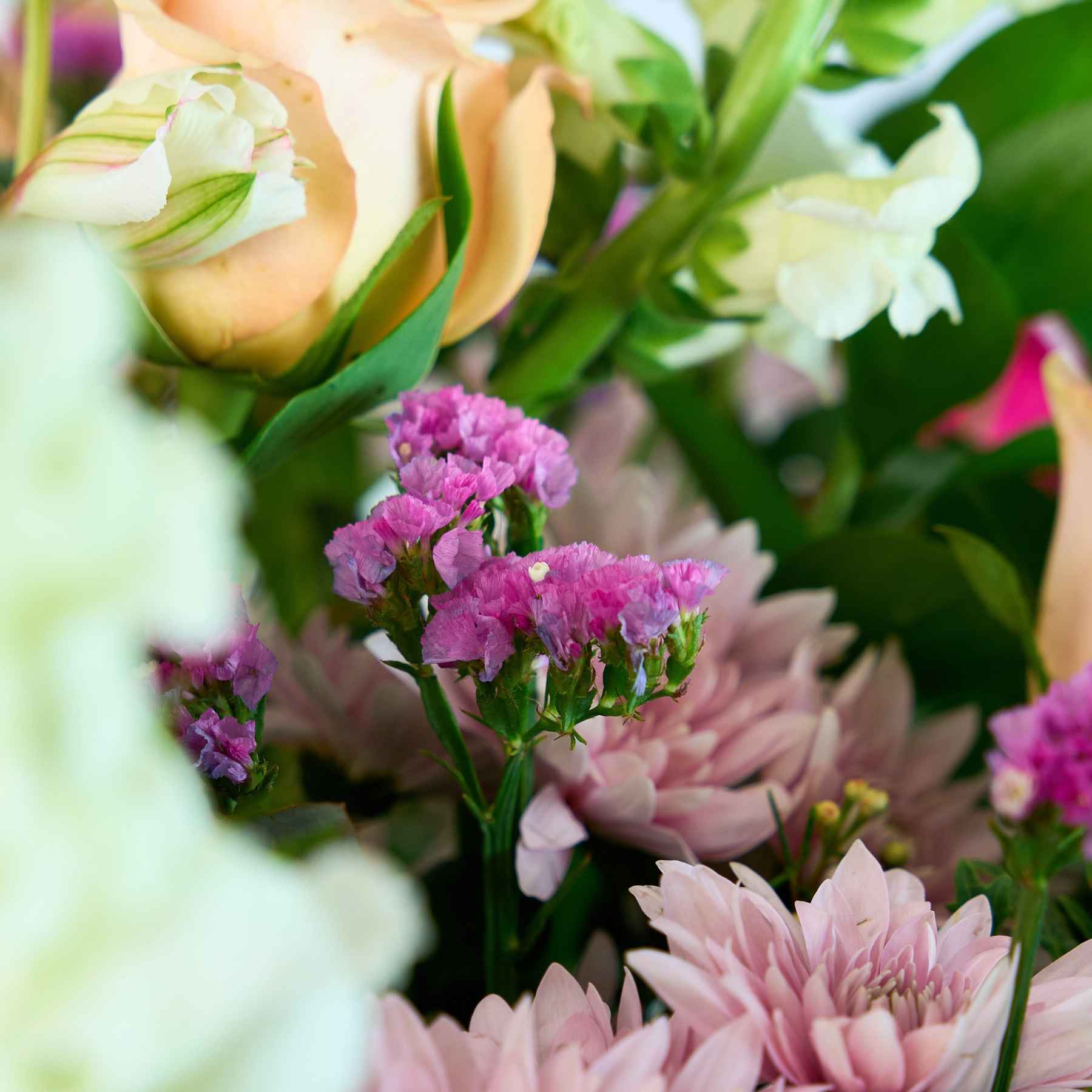 Detailed view of pink and peach flowers within a grand floral arrangement, showcasing the texture and richness of the blooms.