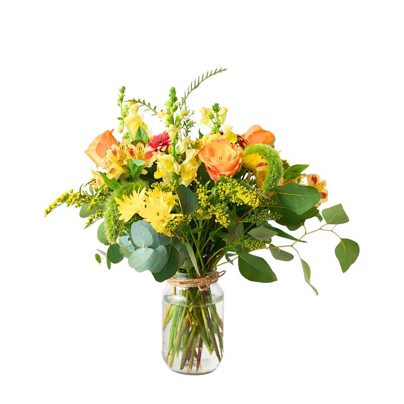 Jar arrangement of flowers in a clear glass vase on a white background
