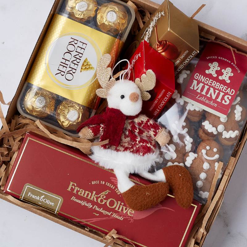 Close-up of the Holiday Bliss Gift Box showcasing Ferrero Rocher, spiced gingerbread biscuits, chocolates, and a cute reindeer decoration.